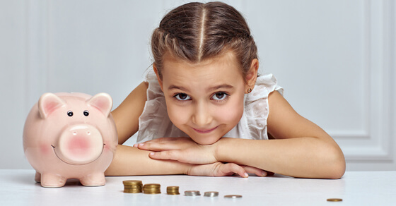 little girl with a piggy bank and some coins