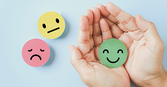 stickers with happy face, sad face, neutral face. Hands holding the happy face sticker