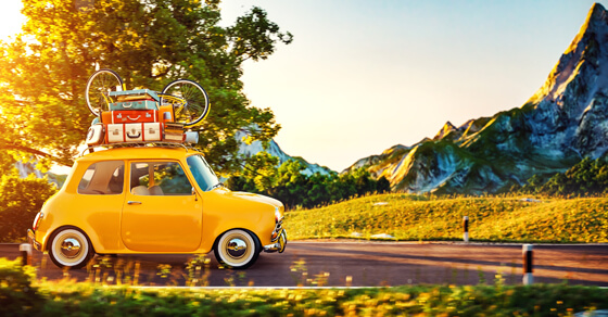 Yellow car with travel gear including a bicycle loaded on the roof