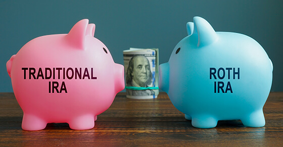 Pink biggy bank with "Traditional IRA" on it facing blue piggy bank with "Roth IRA" written on it